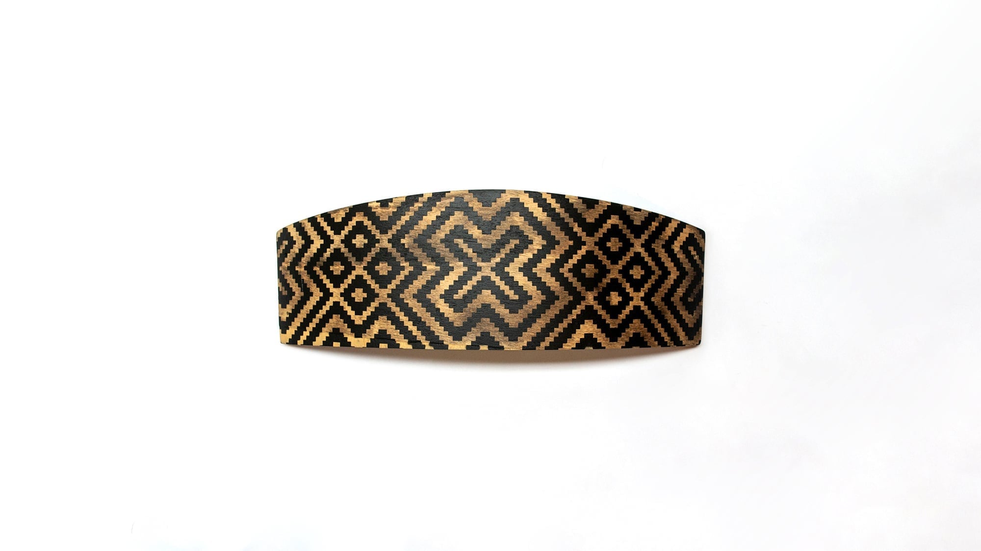 Curved wooden chair backrest featuring black and tan Aztec-inspired geometric pattern with interlocking diamond shapes and stepped motifs