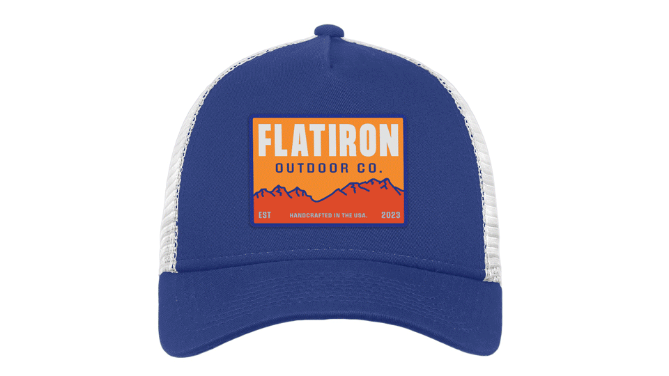 Royal blue trucker hat mockup with white mesh back featuring orange and blue rectangular mountain sunset patch for Flatiron Outdoor Co.