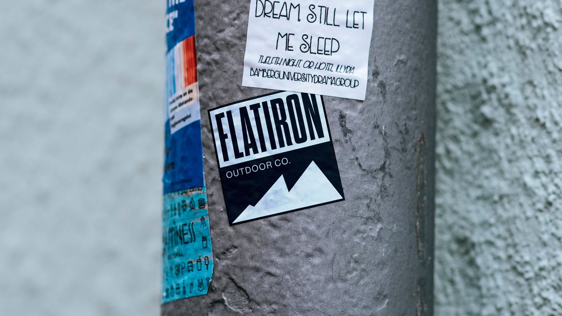 Black and white Flatiron Outdoor Co. vinyl sticker with mountain silhouette applied to urban street pole