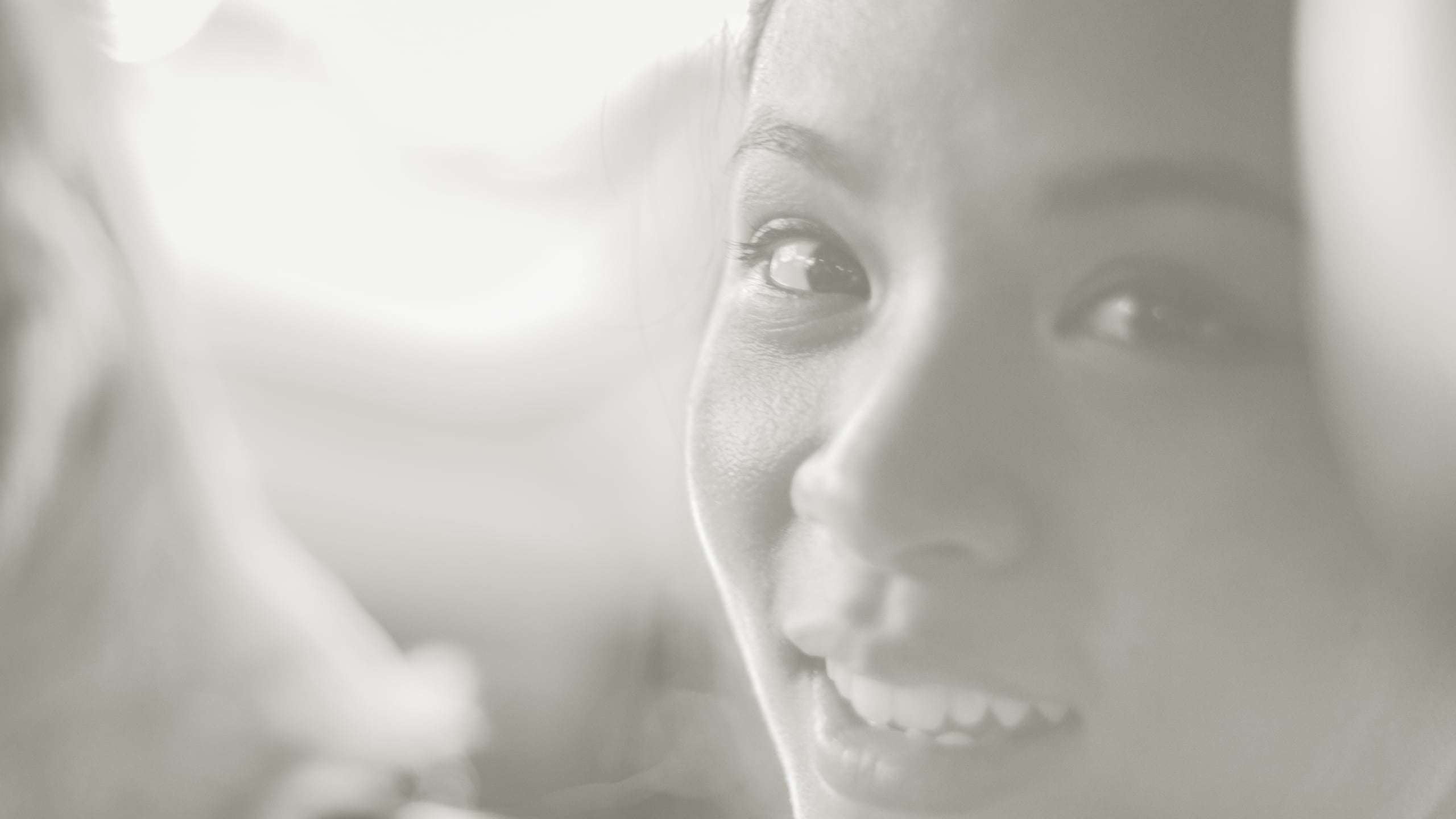 High key black and white close-up portrait of a smiling Asian woman, soft ethereal lighting creating a dreamy overexposed look