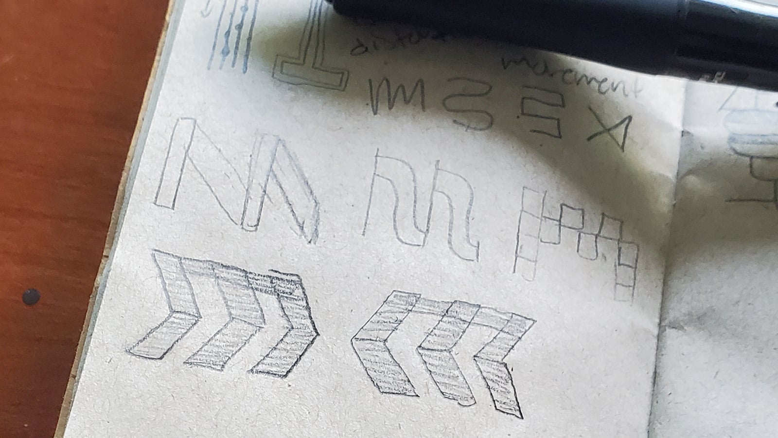 Sketchbook photo with letter M concepts featuring chevron patterns and dimensional arrow forms