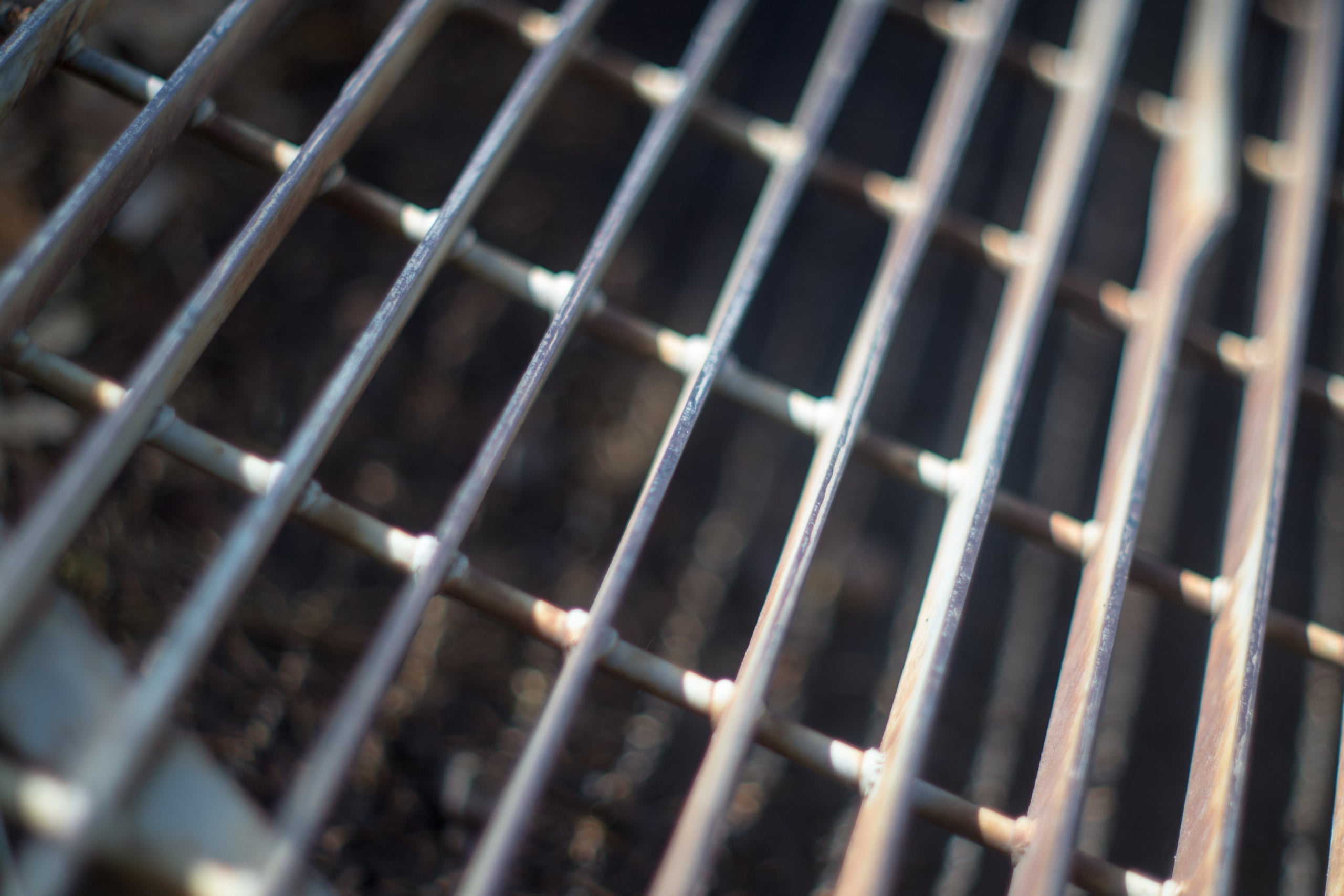 Close-up macro photograph of weathered metal grill grates with diagonal lines creating a geometric pattern and shallow depth of field